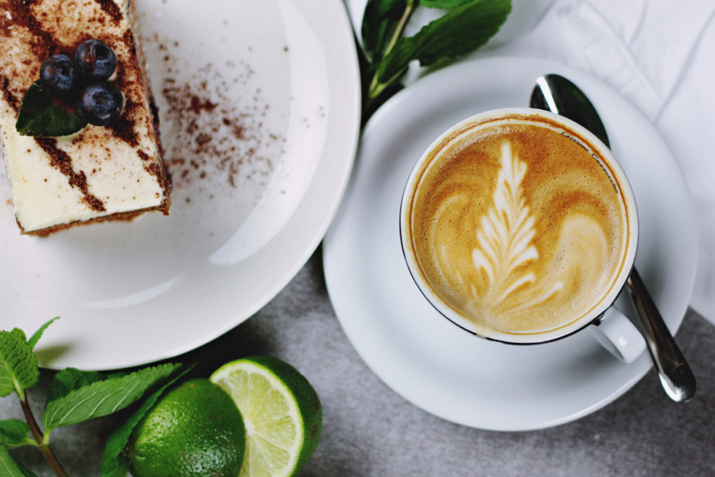 Eine Tasse Cappuccino und ein Stück Kuchen mit Heidelbeeren