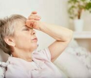Seniorin mit Kopfschmerzen liegt im Bett